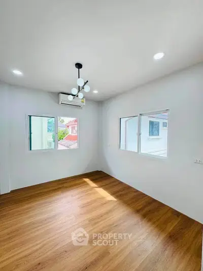 Bright and airy room with wooden flooring and modern lighting, perfect for a cozy living space.
