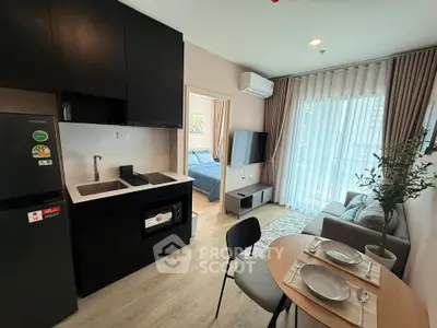 Modern open-plan living room with kitchen and dining area, featuring sleek black cabinetry and cozy decor.