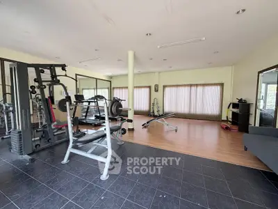 Spacious home gym with modern fitness equipment and large windows for natural light.
