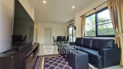 Spacious living room with modern black sofa and large TV, perfect for relaxation and entertainment.