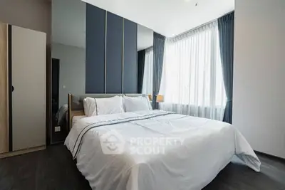 Modern bedroom with large windows and elegant curtains, featuring a comfortable bed and stylish decor.