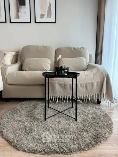 Cozy living room with beige sofa, stylish decor, and soft rug creating a warm ambiance.