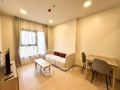 Modern living room with cozy sofa and dining area, bright natural light through large window.