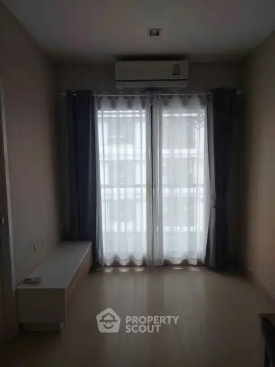 Cozy room with natural light and air conditioning, featuring elegant curtains and wooden flooring.