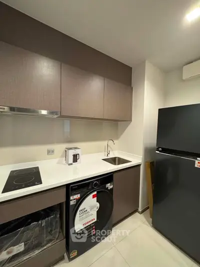 Modern kitchen with sleek appliances and minimalist design, featuring a washing machine and induction cooktop.