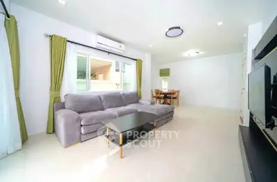 Spacious modern living room with large sofa and dining area, perfect for family gatherings.