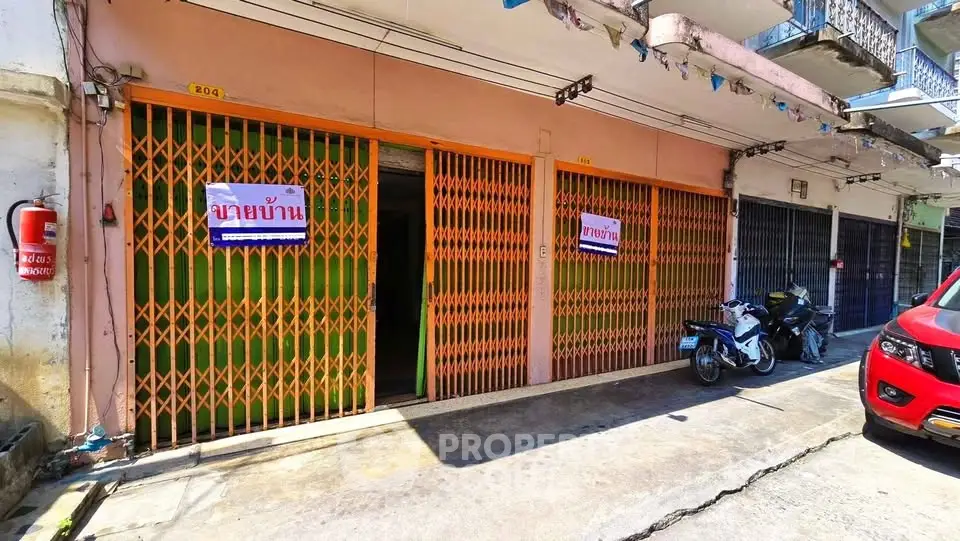 Commercial property with orange metal gates and motorbikes parked outside, ideal for business use.