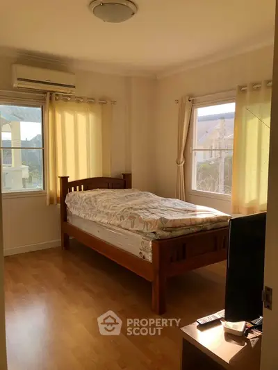 Cozy bedroom with wooden bed frame, natural light, and air conditioning.