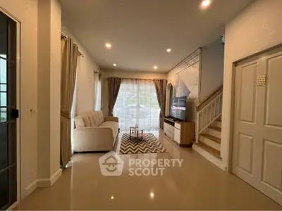 Spacious living room with modern decor and natural light, featuring a cozy sofa and stylish TV setup.