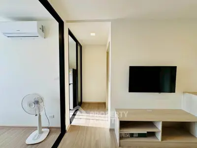 Modern living room with sleek TV setup and air conditioning in a bright apartment.