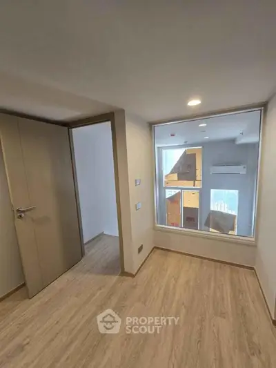 Modern interior room with large window and wooden flooring, perfect for a cozy living space.