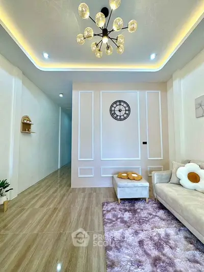 Elegant living room with modern chandelier, plush rug, and stylish wall clock, perfect for cozy gatherings.