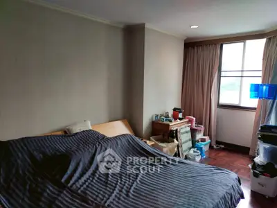 Cozy bedroom with large window and wooden flooring, ideal for relaxation.