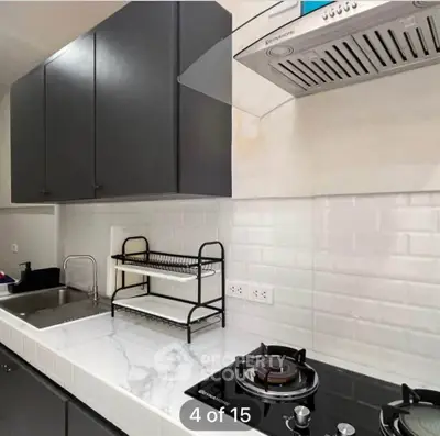 Modern kitchen with sleek cabinets, marble countertop, and gas stove in stylish apartment.