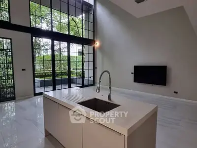 Modern open-plan kitchen with island and large windows overlooking garden.