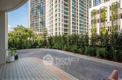 Spacious balcony with city view and lush greenery in modern high-rise building.