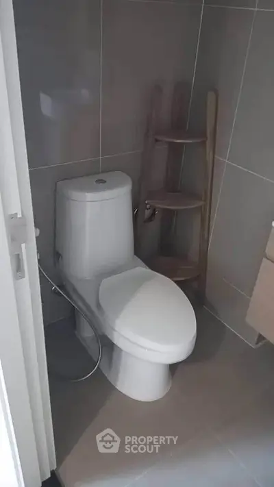 Modern bathroom with sleek toilet and stylish shelving unit.