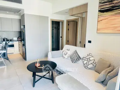 Modern living room with cozy sofa and open kitchen layout in stylish apartment.