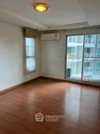 Spacious empty room with wooden flooring and large windows in modern apartment