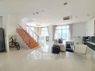 Spacious modern living room with staircase and large windows offering city views