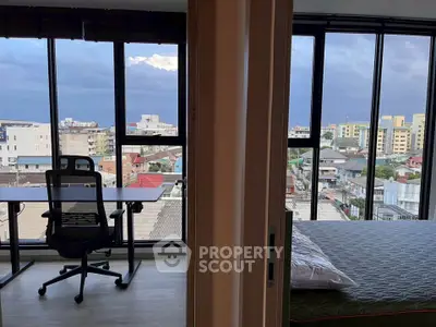 Modern apartment with stunning city view from bedroom and study area, featuring floor-to-ceiling windows.