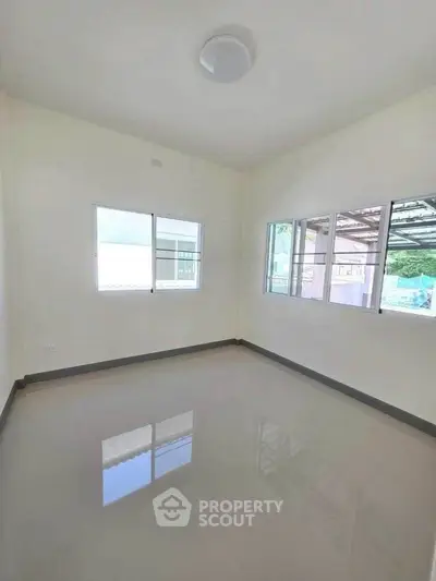 Bright empty room with glossy tiled floor and large windows, perfect for customization.