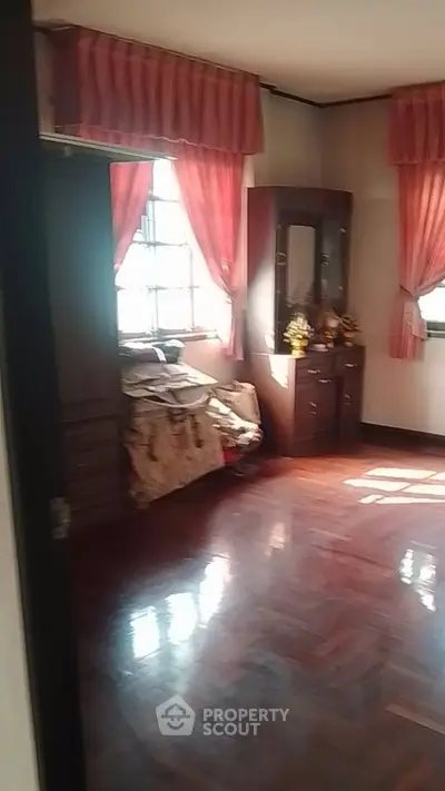 Spacious bedroom with wooden floors and elegant drapery