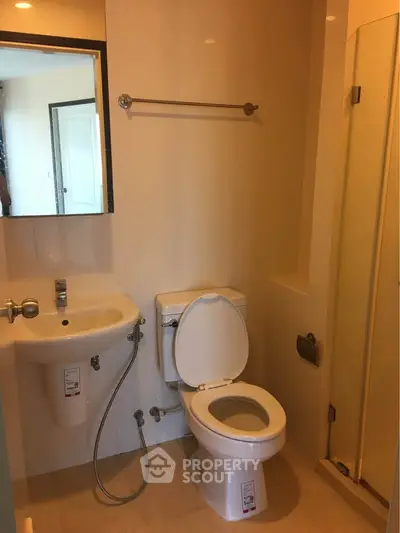 Modern bathroom with shower, toilet, and sink in a compact layout.