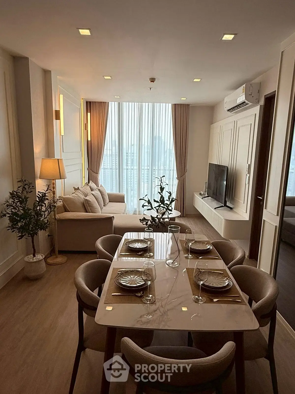 Stylish modern living room with dining area, featuring elegant decor and large windows for natural light.