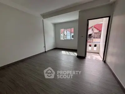 Spacious empty room with balcony and wooden flooring, perfect for customization.