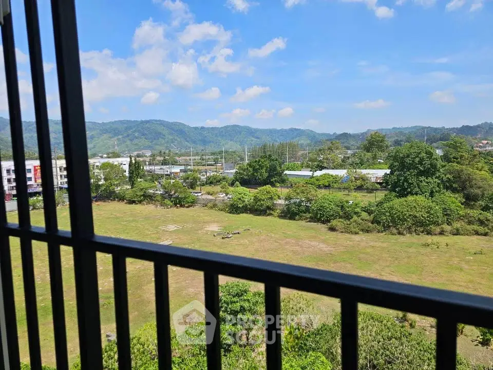 Stunning panoramic view from a high-rise balcony overlooking lush green landscape and distant hills.