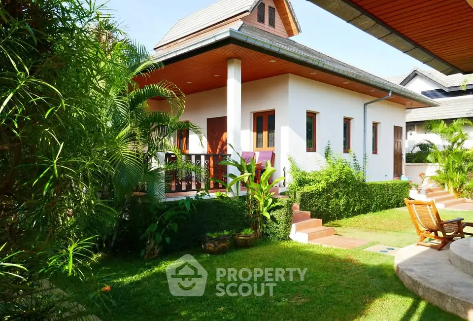 Charming tropical villa with lush garden and inviting outdoor seating area.