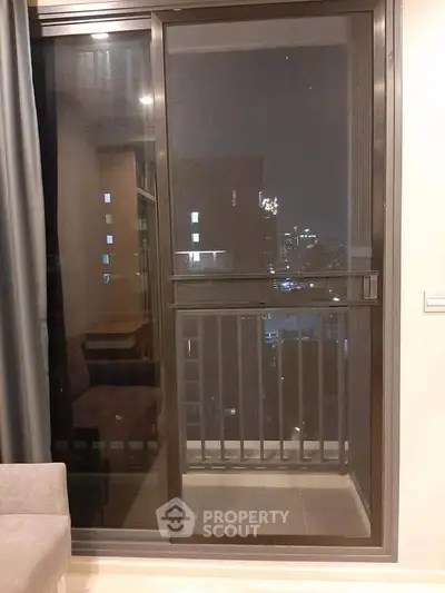 Modern apartment balcony with city night view through glass door.