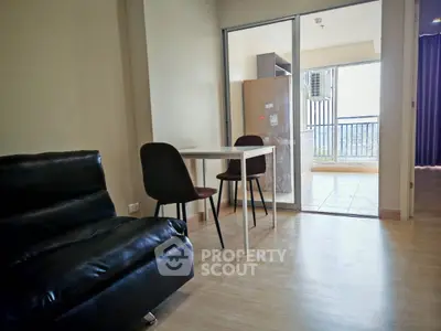 Modern living room with sleek black sofa and dining area leading to a balcony with a view.