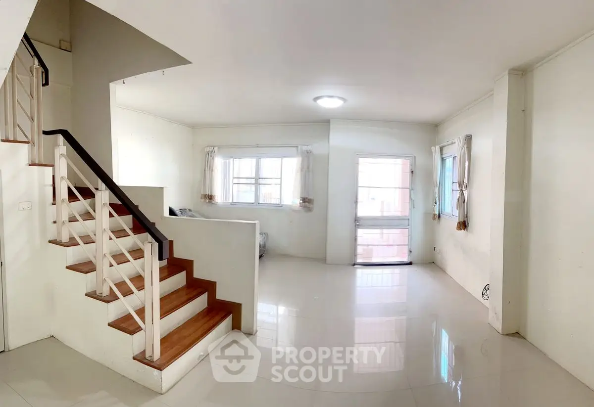 Spacious living room with staircase and large windows in modern home