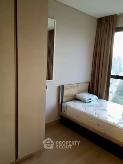 Cozy bedroom with natural light and modern furnishings in a high-rise apartment.