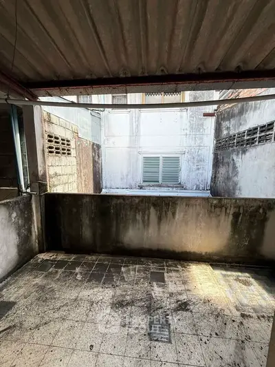 Urban balcony with weathered walls and tiled floor, ideal for renovation.