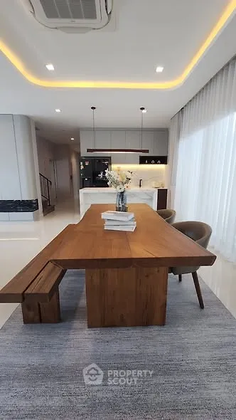 Modern dining area with wooden table and open kitchen layout in luxury apartment.