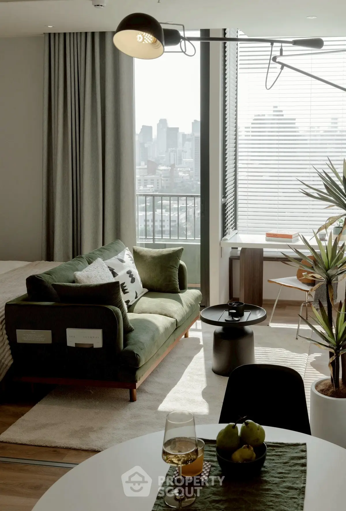 Stylish modern living room with city view, featuring green sofa and elegant decor.