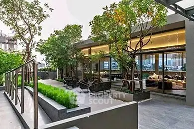 Luxurious modern building exterior with lush greenery and stylish outdoor seating area.
