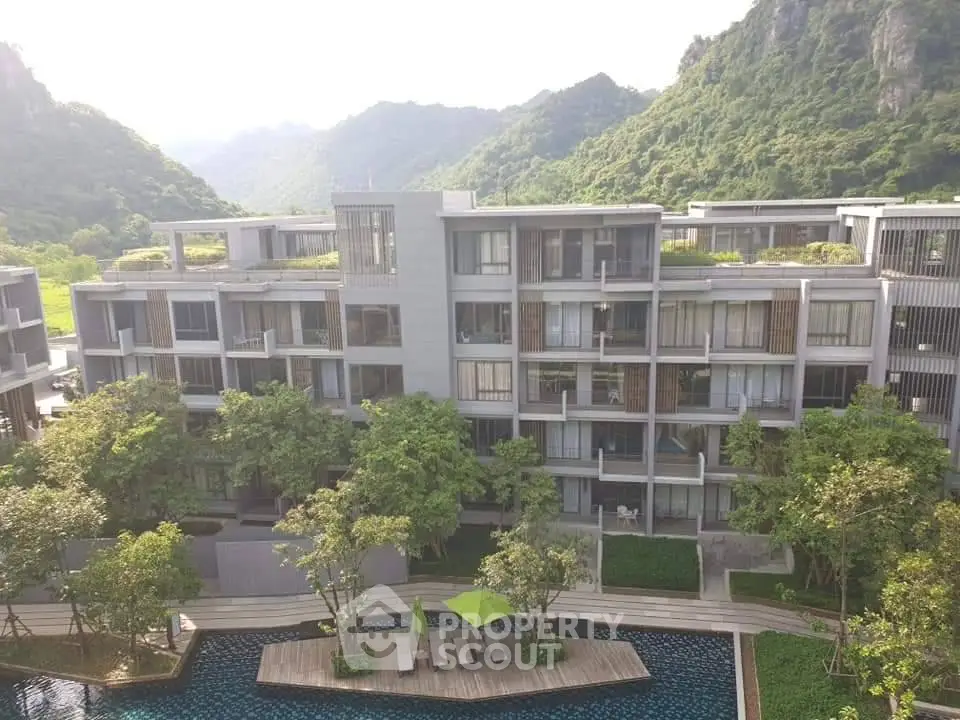 Luxurious modern apartment complex with stunning mountain views and poolside relaxation area.