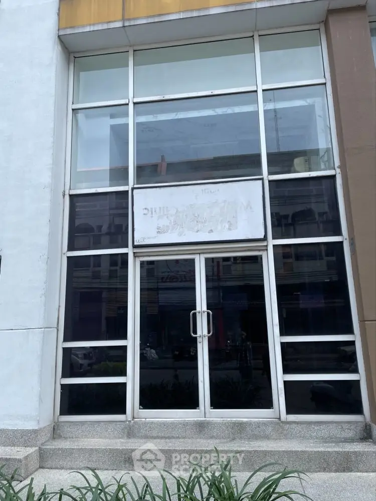 Modern commercial building entrance with large glass doors and windows, ideal for business opportunities.