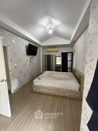 Modern bedroom with stylish decor and mounted TV, featuring a cozy atmosphere.