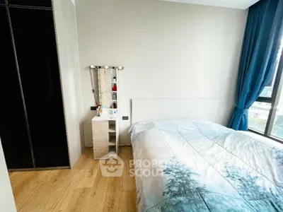 Cozy bedroom with modern decor and large window offering natural light.