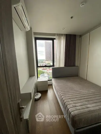 Cozy bedroom with large window offering city view, featuring modern bed and air conditioning.