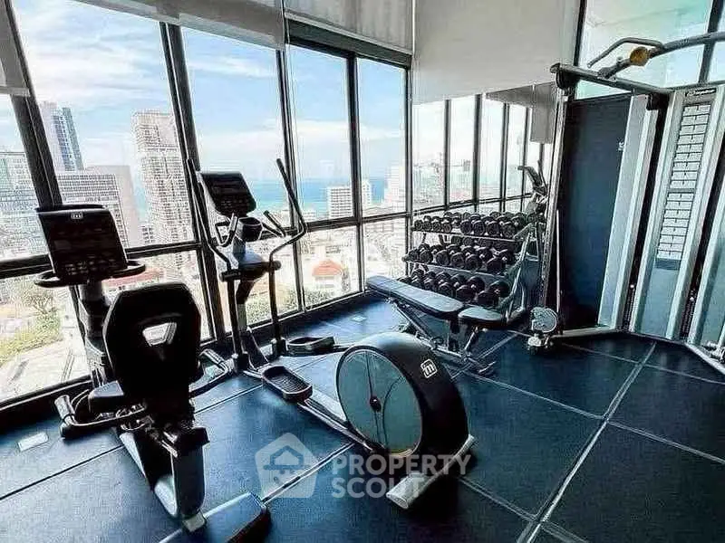 Luxurious high-rise gym with panoramic city and ocean views, featuring modern fitness equipment.