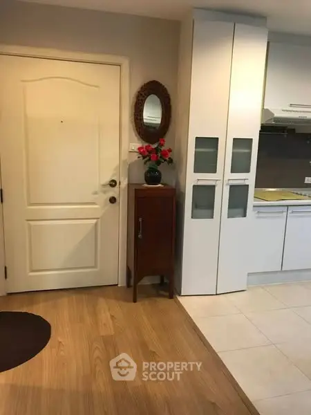 Charming entryway with modern kitchen view, featuring sleek cabinets and stylish decor.