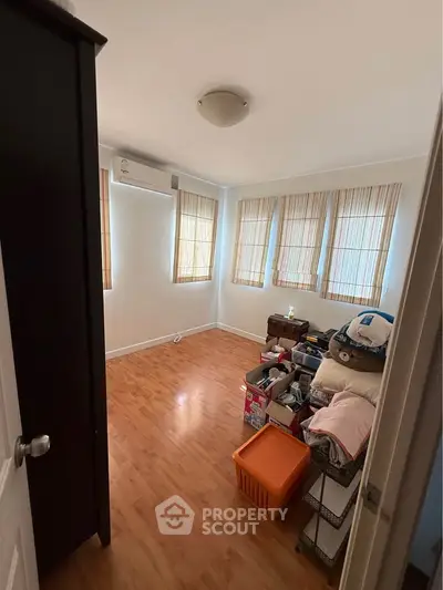 Cozy bedroom with wooden flooring and ample natural light from multiple windows.