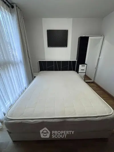 Spacious bedroom with modern furniture and large window for natural light.