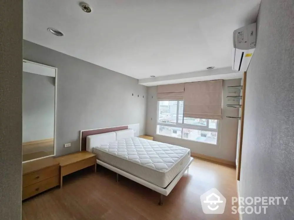 Spacious bedroom with modern design and large window offering natural light.